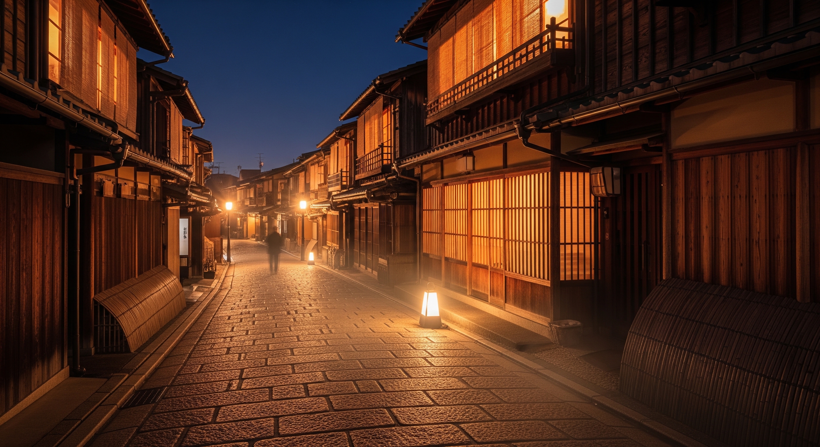 Lantern-lit stone-paved street in Gion at night, traditional machiya townhouses glowing amber
